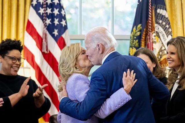 President Joe Biden, accompanied by Office of Management and Budget director Shalanda Young, left, and Women's Alzheimer's Movement founder Maria Shriver, right, gives first lady Jill Biden a kiss after giving her the pen he used to sign a presidential memorandum that will establish the first-ever White House Initiative on Women's Health Research in the Oval Office of the White House, Monday, November 13, 2023, in Washington. (Photo by Andrew Harnik/AP Photo)