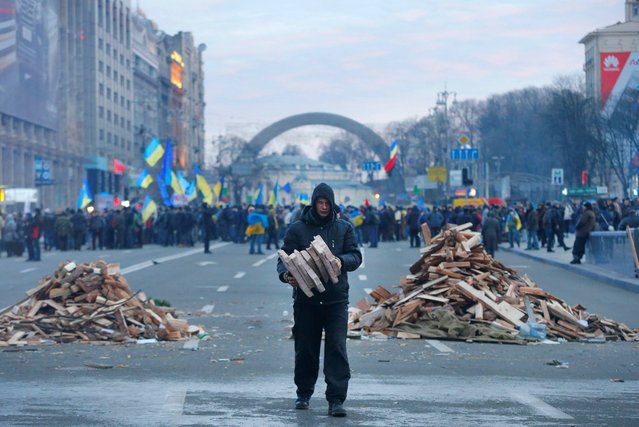 A protester collects firewood for heating in downtown Kiev, Ukraine, early Wednesday, December 4, 2013. Ukraine's opposition failed to force out the government with a parliamentary no-confidence vote Tuesday, leaving political tensions unresolved and a potential standoff between protesters and the country's leaders looming. (Photo by Sergei Grits/AP Photo)