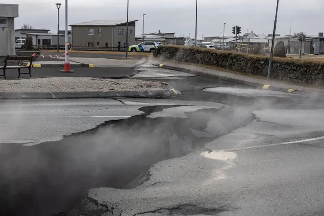 Smoke rises from the crack in a road in the fishing town of Grindavik, which was evacuated due to volcanic activity, in Iceland on November 15, 2023. (Photo by Marko Djurica/Reuters)