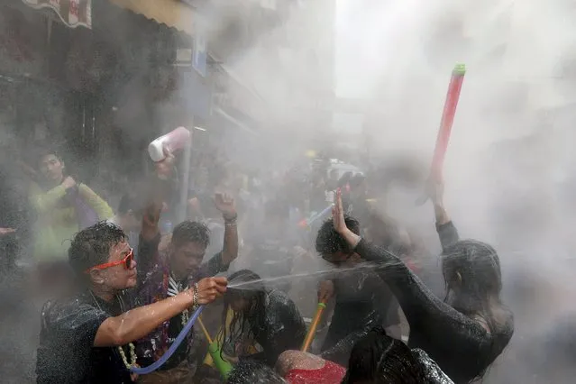 Revellers take part in a water fight during Songkran Festival celebrations at Kowloon City district is known as Little Thailand as there is large number of restaurants and shops run by Thais April 12, 2015. The Songkran festival, also known as the water festival, marks the start of Thailand's traditional New Year and is believed to wash away bad luck. (Photo by Tyrone Siu/Reuters)