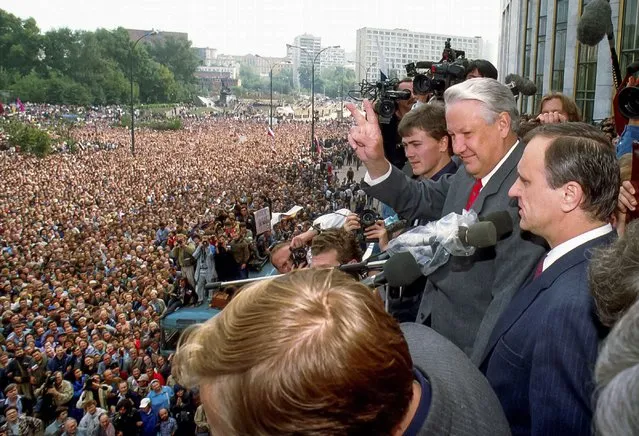 In this Thursday, August 22, 1991 file photo, Russian Republic President Boris Yeltsin, second right, makes a V-sign to thousands of Muscovites, as his top associate Gennady Burbulis stands near, during a rally in front of the Russian federation building to celebrate the failed military coup in Moscow, Russia. (Photo by Alexander Zemlianichenko/AP Photo/file)