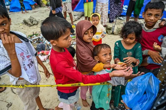 Rohingya refugees receive food donations at a beach on Sabang island, Indonesia's Aceh province on December 3, 2023. More than 100 Rohingya refugees, including women and children, landed in Indonesia's westernmost province on December 2, officials said, but locals threatened to push them back to sea. (Photo by Chaideer Mahyuddin/AFP Photo)