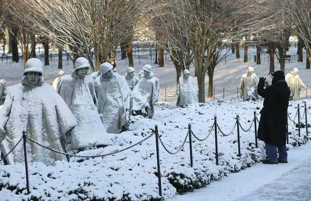 A man photographs the Korean War Veterans Memorial after a heavy snow storm in Washington January 3, 2014. A heavy snowstorm and dangerously cold conditions gripped the northeastern United States on Friday, delaying flights, paralyzing road travel and closing schools and government offices across the region. (Photo by Gary Cameron/Reuters)