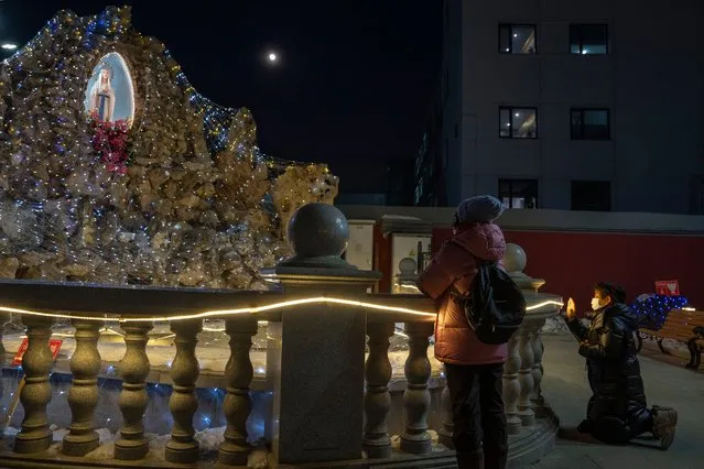 A faithful prays near a statue of the Virgin Mary outside the Xishiku Catholic Church on Christmas Day in Beijing, Monday, December 25, 2023. (Photo by Ng Han Guan/AP Photo)