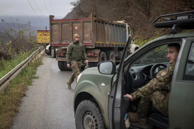 Latvian soldiers part of the NATO-led peackeeping mission in Kosovo patrol near heavy vehicles parked by local Serbs blocking the road near the village of Uglare, in northern Kosovo on Monday, December 12, 2022. Barricades erected by local Serbs in the north of Kosovo remained up on Monday for the third consecutive day, despite calls from the international community to be removed and the situation de-escalated. Kosovo on Saturday postponed a local election due Dec. 18 in four municipalities with a predominantly ethnic Serb population, in an effort to defuse recent tensions there that have also caused relations with neighboring Serbia to deteriorate further. (Photo by Visar Kryeziu/AP Photo)