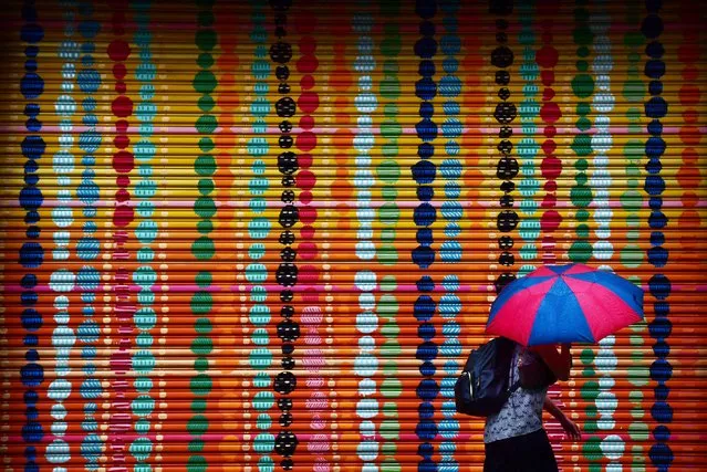 A pedestrian passes a colorfully painted door as rain falls in Alexandria, Va. on September 20, 2018. (Photo by Matt McClain/The Washington Post)