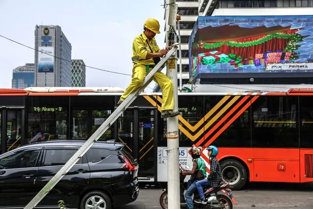 A technician works on a street light at a busy intersection in Jakarta, Indonesia, 01 January 2024. Indonesia's economy is expected to grow 5 percent in 2024, the Asian Development Bank (ADB) forecasted. (Photo by Mast Irham/EPA)