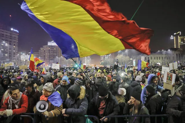 A man waves a large Romanian flag during a protest joined by tens of thousands against a government decree that dilutes what qualifies as corruption, in Bucharest, Romania, Thursday, February 2, 2017. Huge protests erupted in the capital and spread to cities around Romania in the past two nights after the government changed the law – one of the biggest protests in Romania since communism ended in 1989. (Photo by Vadim Ghirda/AP Photo)