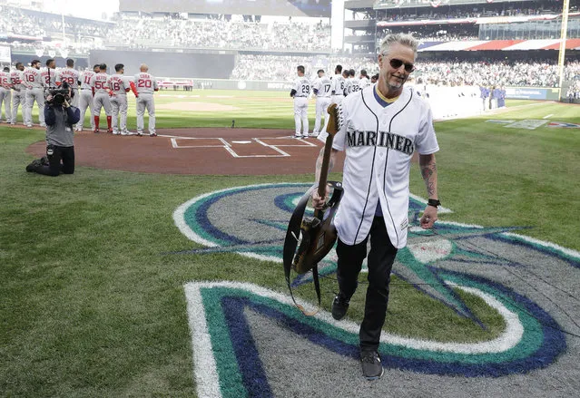 Pearl Jam guitarist Mike McCready carries his guitar after performing the national anthem before a baseball game between the Seattle Mariners and the Boston Red Sox, Thursday, March 28, 2019, in Seattle. (Photo by Ted S. Warren/AP Photo)