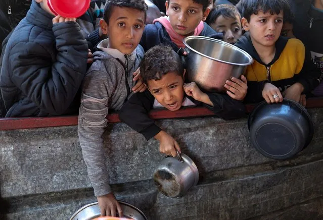 Palestinian children wait to receive food cooked by a charity kitchen amid shortages of food supplies, as the ongoing conflict between Israel and the Palestinian Islamist group Hamas continues, in Rafah, in the southern Gaza Strip, on February 5, 2024. (Photo by Ibraheem Abu Mustafa/Reuters)