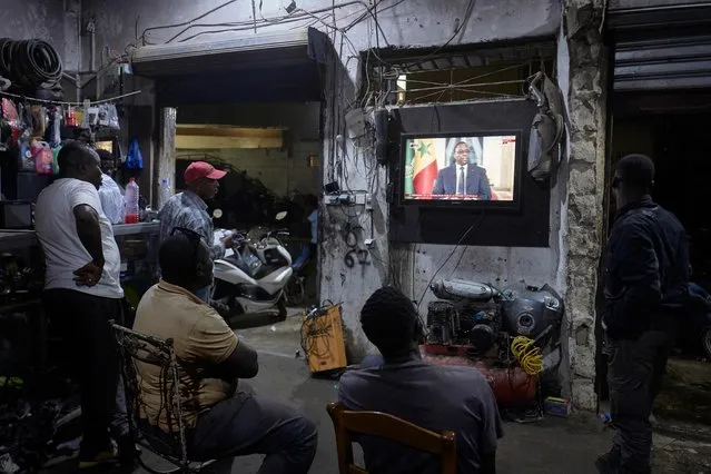 People watch the Senegal's President Macky Sall during a live press conference broadcast on the national television, in the district of Medina in Dakar on February 22, 2024. Senegal's outgoing President Macky Sall on February 22, 2024, said his mandate would end as planned on April 2, but left open the date of the presidential election which he postponed earlier this month. (Photo by Michele Cattani/AFP Photo)