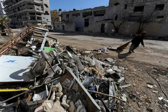 A woman walks past debris along a street in Aleppo's Belleramoun Industrial Zone, Syria February 2, 2017. (Photo by Omar Sanadiki/Reuters)