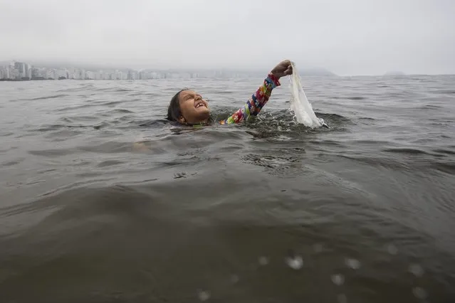 Nina Gomes collects garbage from the sea near Copacabana beach in Rio de Janeiro, Brazil, Tuesday, March 19, 2024. For years Gomes has been accompanying her father, Ricardo Gomes, a biologist and director of the Mar Urbano Institute, to collect garbage from the city's beaches and seawater. (Photo by Bruna Prado/AP Photo)