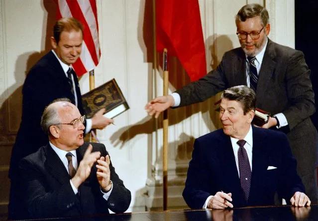 Soviet leader Mikhail Gorbachev applauds during a treaty-signing ceremony with President Ronald Reagan in the White House East Room, December 8, 1987.  Reagan and Gorbachev signed an historic treaty to eliminate intermediate-range missiles and together vowed to work toward a more ambitious arms control pact during their three days of meetings. Others are unidentified. (Photo by Bob Daugherty/AP Photo)