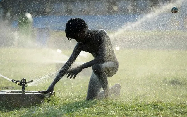 An Indian boy plays with water sprinklers at Marina Beach during a hot day in Chennai on May 27, 2019. (Photo by Arun Sankar/AFP Photo)