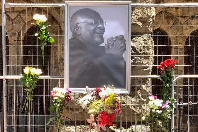 Flowers are seen next to a portrait of South African anti-apartheid icon Desmond Tutu outside St. George's cathedral in Cape Town on December 26, 2021, after the news of Tutu's passing. South African anti-apartheid icon Desmond Tutu, described as the country's moral compass, died on December 26, 2021, aged 90, President Cyril Ramaphosa said. (Photo by Gianluigi Guercia/AFP Photo)