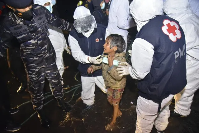 Medical workers help a Rohingya young girl upon arrival at Krueng Geukueh Port in North Aceh, Indonesia, early Friday, December 31, 2021. A group of 120 Rohingya Muslims disembarked from a boat that had drifted for days off Indonesia's northernmost province of Aceh and was towed by a navy ship into port, officials said Friday. (AP Photo/Rahmat Mirza)