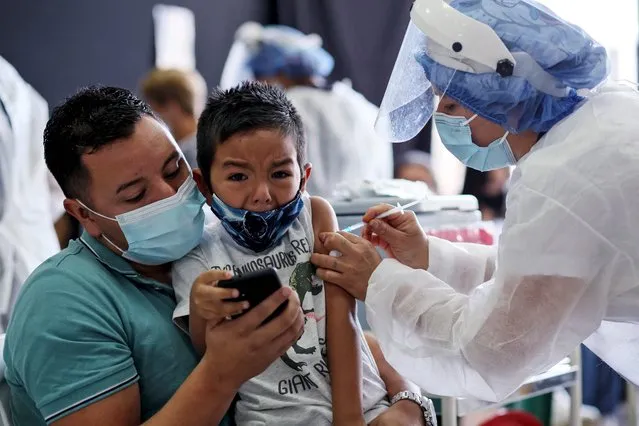 A health worker inoculates a boy with the CoronaVac vaccine, developed by China's Sinovac against the novel coronavirus disease COVID-19, at a vaccination centre in Bogota, on January 4, 2022, as the World Health Organization (WHO) warned that Omicron's dizzying spread increased the risk of newer, more dangerous variants emerging. (Photo by Leonardo Munoz/AFP Photo)