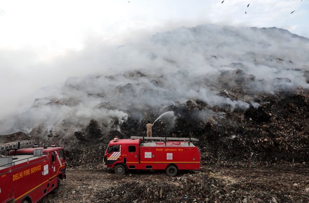 Indian fire fighters try to extinguish a fire that broke out at a garbage landfill site in Ghazipur, New Delhi, India, 22 April 2024. Residents around the landfill are facing poor visibility and breathing issues due to the potentially toxic plumes of smoke. (Photo by Rajat Gupta/EPA)