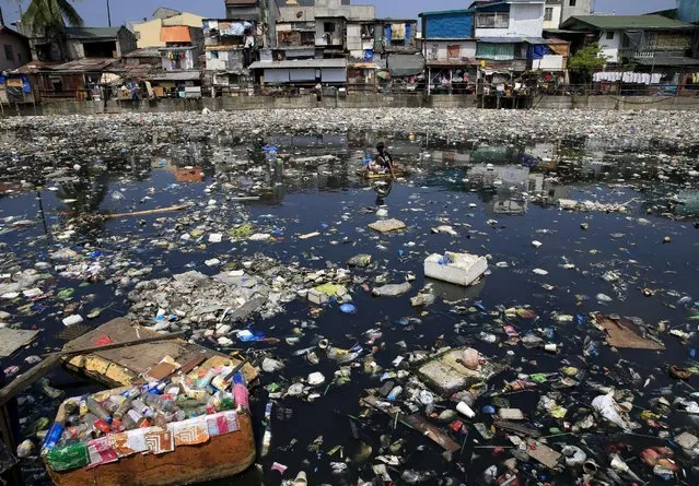 A scavenger wades through a polluted river using a makeshift raft made of styrofoam to collect reusable items at Capulong Tondo, metro Manila April 22, 2016. (Photo by Romeo Ranoco/Reuters)