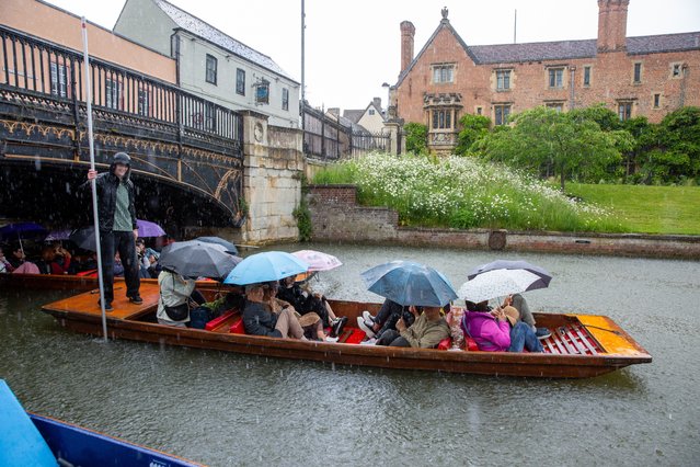 People huddle under umbrellas on a punt on the River Cam in Cambridge, UK as the rain pours on Sunday morning, May 26, 2024. (Photo by Geoff Robinson Photography)