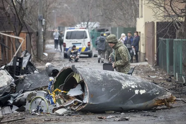 A Ukrainian Army soldier inspects fragments of a downed aircraft in Kyiv, Ukraine, Friday, February 25, 2022. It was unclear what aircraft crashed and what brought it down amid the Russian invasion in Ukraine. Russia is pressing its invasion of Ukraine to the outskirts of the capital after unleashing airstrikes on cities and military bases and sending in troops and tanks from three sides. (Photo by Vadim Zamirovsky/AP Photo)