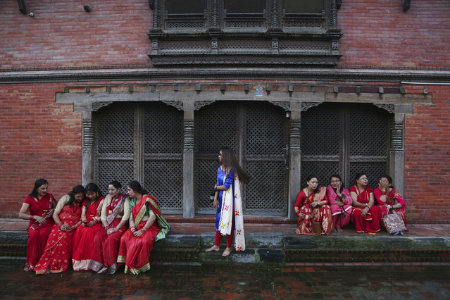 Nepalese Hindu women take rest at the Pashupatinath temple during Teej festival celebrations in Kathmandu, Nepal, Monday, September 2, 2019. During this festival, Hindu women observe a day-long fast and pray for their husbands and for a happy married life. Those who are unmarried pray for a good husband. (Photo by Niranjan Shrestha/AP Photo)