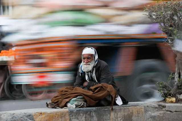 A man bundles up to avoid the cold as he sits on a road median in Karachi, Pakistan, January 24, 2022. (Photo by Akhtar Soomro/Reuters)