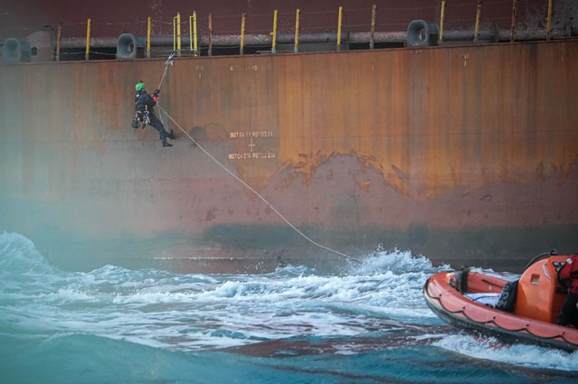 An activist of the environmental NGO Greenpeace climbs to take part in an action on a Shell platform, on the way to the North Sea, to expand an existing oil and gas field, off the coast of Cherbourg, northwestern France, on February 6, 2023. (Photo by Lou Benoist/AFP Photo)