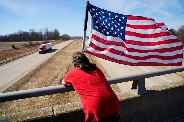 Dave Woods, 47, waits on an overpass in support for trucks driving in a convoy bound for the nation's capital to protest against coronavirus disease (COVID-19) vaccine mandates, in Wabash Township, Illinois, U.S. March 1, 2022. (Photo by Cheney Orr/Reuters)