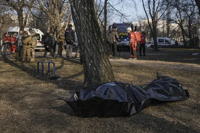 The body of a victim on the ground after a bombing in a residential area in Kyiv, Ukraine, Tuesday, March 15, 2022. Russia's offensive in Ukraine has edged closer to central Kyiv with a series of strikes hitting a residential neighborhood as the leaders of three European Union member countries planned a visit to Ukraine's embattled capital. (Photo by Vadim Ghirda/AP Photo)