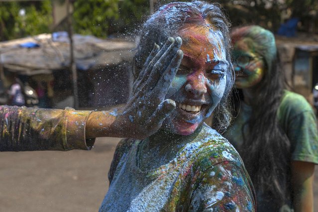 A man applies colored powder on his friend's face during celebrations marking Holi, the Hindu festival of colors, in Mumbai, India, Tuesday, March 7, 2023. The festival heralds the arrival of spring. (Photo by Rafiq Maqbool/AP Photo)