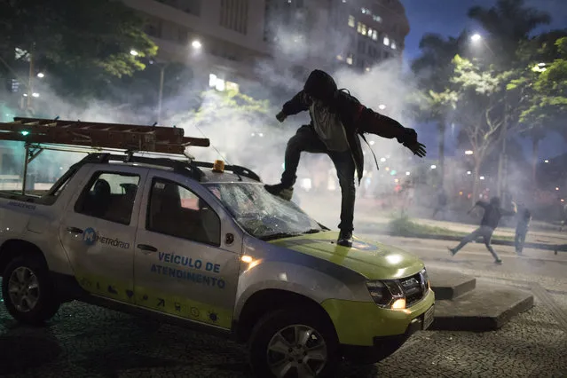 A demonstrator breaks the windshield of a truck that belongs to a subway maintenance crew after clashes with police broke out during a general strike in Rio de Janeiro, Brazil, Friday, April 28, 2017. Public transport largely came to a halt across much of Brazil on Friday and protesters blocked roads and scuffled with police as part of a general strike to protest proposed changes to labor laws and the pension system. (Photo by Leo Correo/AP Photo)