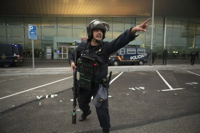 In this Monday, October 14, 2019 photo, a Spanish police gives instructions to other police members, not pictured, during a demonstration at El Prat airport, outskirts of Barcelona, Spain. Riot police engaged in a running battle with angry protesters outside Barcelona's airport Monday after Spain's Supreme Court convicted 12 separatist leaders of illegally promoting the wealthy Catalonia region's independence and sentenced nine of them to prison. (Photo by Joan Mateu/AP Photo)