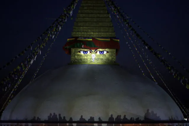 In this Tuesday, April 25, 2017, photo, shadows of Nepalese people are cast on the Boudhanath stupa as they light candles to mark the second anniversary of a devastating earthquake in Kathmandu, Nepal. Two years ago, Nepal was ravaged by a massive 7.8-magnitude earthquake that killed nearly 9,000 people and left another 4 million homeless as their humble homes built from brick and stone were toppled within seconds. (Photo by Niranjan Shrestha/AP Photo)