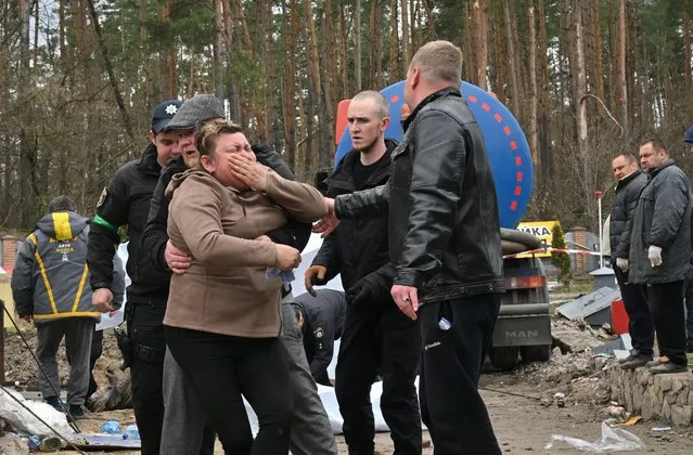 A Ukrainian mother reacts after the body of her son was discovered in a manhole at a petrol station in the outskirts of the Buzova village, west of Kyiv, on April 10, 2022. At least two bodies, appearing to be clad in a mix of civilian and military clothing, were discovered in a manhole at the back of a destroyed motorway petrol station. (Photo by Sergei Supinsky/AFP Photo)