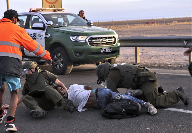 A migrant is detained by Chilean Police for blocking the highway on the Chile-Peru border, near Arica, Chile, Tuesday, May 2, 2023. A migration crisis at the border between Chile and Peru has intensified as migrants who claim they want to go home remained stranded, unable to enter Peru. (Photo by Agustin Mercado/AP Photo)