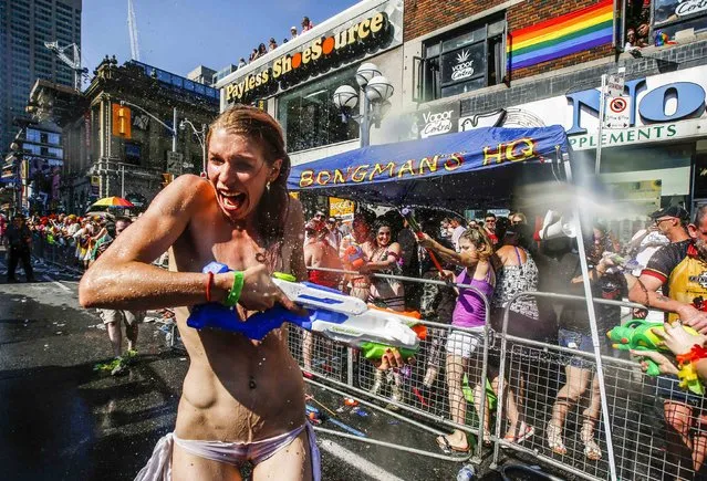A topless woman gets sprayed by water guns during the “WorldPride” gay pride Parade in Toronto June 29, 2014. Toronto is hosting WorldPride, a week-long event that celebrates the lesbian, gay, bisexual and transgender (LGBT) community. (Photo by Mark Blinch/Reuters)