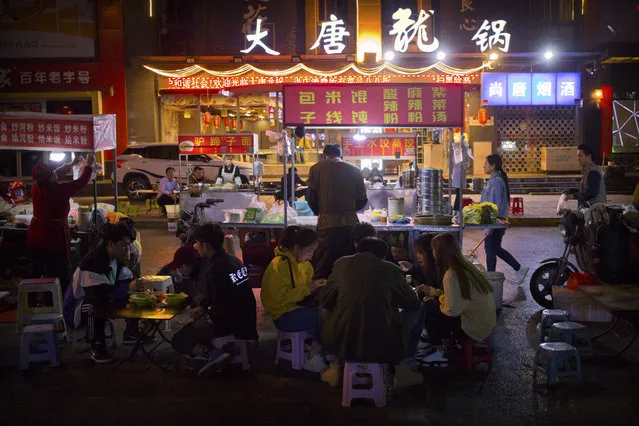 In this March 27, 2019, photo, people eat at an outdoor night market in Xi'an, northwestern China's Shaanxi Province, similar to one at which Yin Hao, who also goes by Yin Qiang, was injured during a fight that led to his initial prescription for Tylox. Officially, pain pill abuse is an American problem, not a Chinese one. But people in China have fallen into opioid abuse the same way many Americans did, through a doctor's prescription. And despite China's strict regulations, online trafficking networks, which facilitated the spread of opioids in the U.S., also exist in China. (Photo by Mark Schiefelbein/AP Photo)