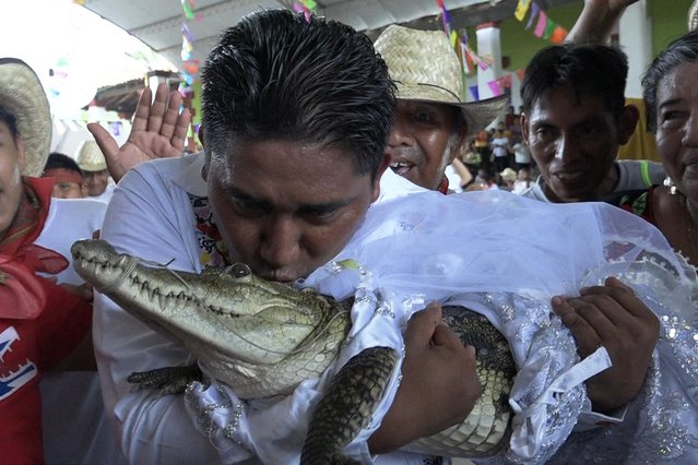 Victor Hugo Sosa, Mayor of San Pedro Huamelula, kisses a spectacled caiman (Caiman crocodilus) called “La Niña Princesa” (”The Princess Girl”) before marrying her in San Pedro Huamelula, Oaxaca state, Mexico on June 30, 2023. This ancient ritual of more than 230 years unites two ethnic groups in marriage to bring prosperity and peace. The spectacled caiman (Caiman crocodilus) is paraded around the community before being dressed as a bride and marrying the Mayor. According to beliefs, this union between the human and the divine will bring blessings such as a good harvest and abundant fishing. (Photo by Rusvel Rasgado/AFP Photo)