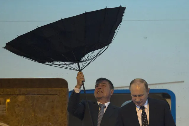 A security personnel struggles with an umbrella as Russia's President Vladimir Putin walks out of a plane upon arriving at the airport ahead of the fourth summit of the Conference on Interaction and Confidence Building Measures in Asia (CICA) held in Shanghai, May 20, 2014. (Photo by Ng Han Guan/Reuters)