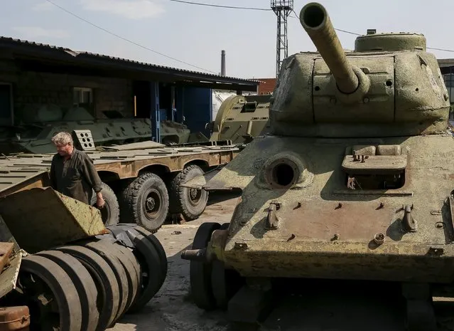 A worker walks pass an old soviet tank T-34 (R) as he fixes military vehicle (L) at Phaeton museum in Zaporizhia, Ukraine, August 11, 2015. (Photo by Gleb Garanich/Reuters)