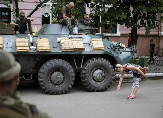 A local woman greets Ukrainian soldiers in central Slaviansk July 15, 2014. The city, which the government wrested control from pro-Russian separatists 10 days ago, suffers from a lack of electricity and water, local media reported. Ukraine has made fresh charges of Russian involvement in its conflict with separatist rebels, suggesting Moscow may have had a role in an air strike on Tuesday that killed 11 people. (Photo by Gleb Garanich/Reuters)