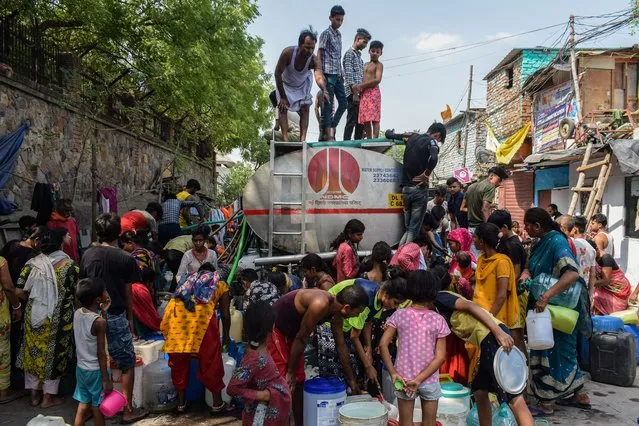 People fill water containers with drinking water from a Municipal Water Tanker outside a slum cluster in New Delhi on June 15, 2022. The demand for drinking water has increased due to many heatwaves in Delhi. (Photo by Kabir Jhangiani/Pacific Press/Rex Features/Shutterstock)