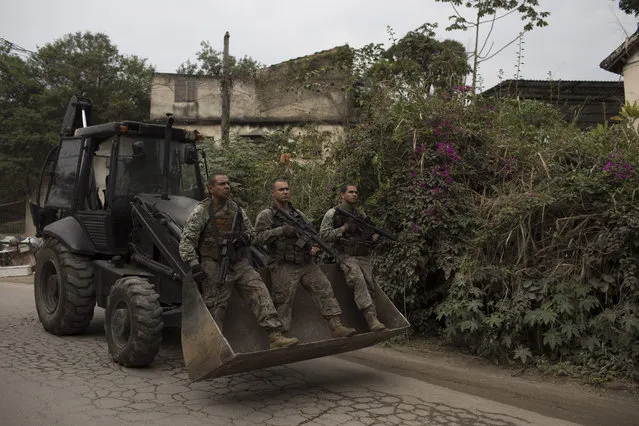 Police officers of the special operations battalion ride on a mechanical shovel during a patrol at the Caramujo slum in Niteroi, Brazil, Wednesday, August 16, 2017. Thousands of soldiers and police began patrolling metropolitan region of Rio de Janeiro as part of security actions to diminish the violence in the state. (Photo by Leo Correa/AP Photo)