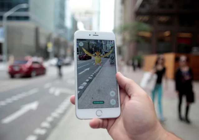 A “Pidgey” Pokemon is seen on the screen of the Pokemon Go mobile app, Nintendo's new scavenger hunt game which utilizes geo-positioning, in a photo illustration taken in downtown Toronto, Ontario, Canada July 11, 2016. (Photo by Chris Helgren/Reuters)