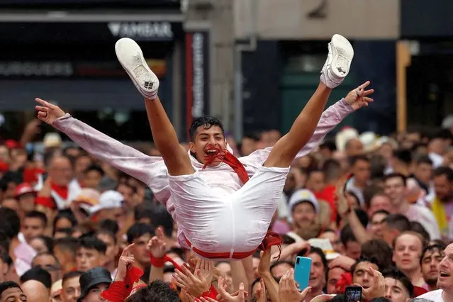 A reveller is thrown into air by others during the opening of the San Fermin festival in Pamplona, Spain on, July 6, 2022. (Photo by Juan Medina/Reuters)