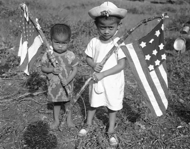 Tiny natives of Guam hold home-made American flags made by their mothers from parts of dresses while in custody of the Japanese, August 10, 1944. The children waved the flags when the Yanks moved in. (Photo by Joe Rosenthal/AP Photo)