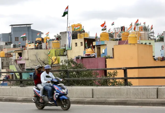 Motorists drive past houses hanging the Indian tricolour flag during the 75th years of India's Independence or “Azadi Ka Amrit Mahotsav” in Bangalore, India, 15 August 2022. (Photo by Jagadeesh N.V./EPA/EFE)
