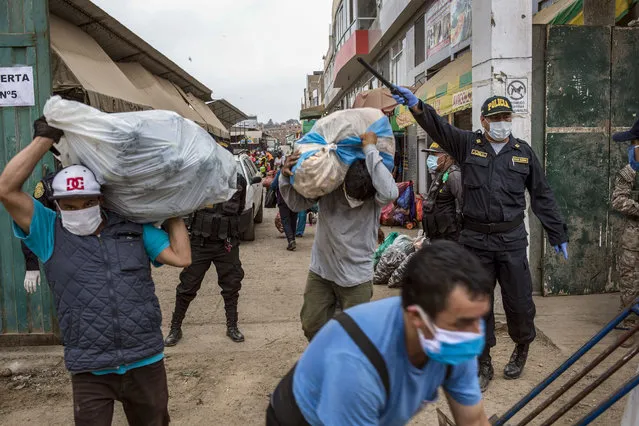 Police, wearing protective face coverings as a precaution to curb the spread of the new coronavirus, direct the entrance and exit of customers at a popular market in Lima, Peru, Saturday, April 11, 2020. (Photo by Rodrigo Abd/AP Photo)